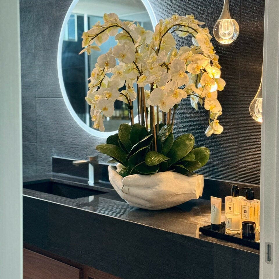 Orquídeas Phalaenopsis blancas en jarrón con la escultura «Manos abiertas»